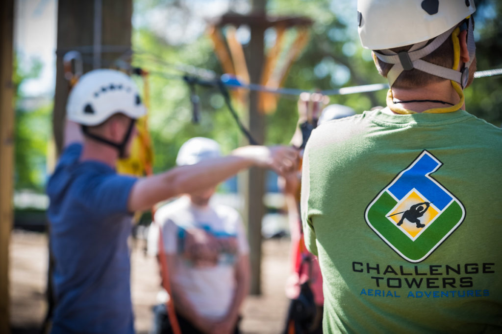 Man in a green Challenge Towers t-shirt wearing a helmet.