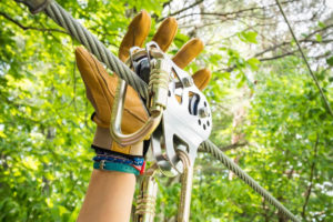 Hand reaching up onto a rope trolly device.