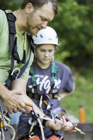 CampGreystone-316 Trainer explaining how a belay system works.