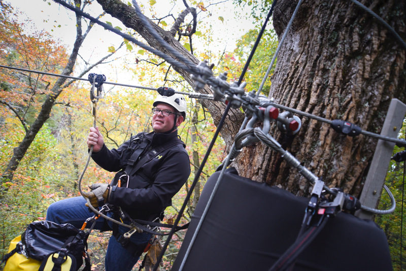 Man standing on edge of zipline platform.