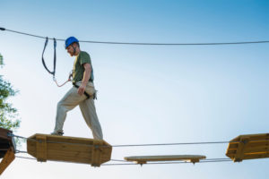 man-traversing-challenge-course-element-challenge-towers-wild-blue-aerial-adventures-banner-size