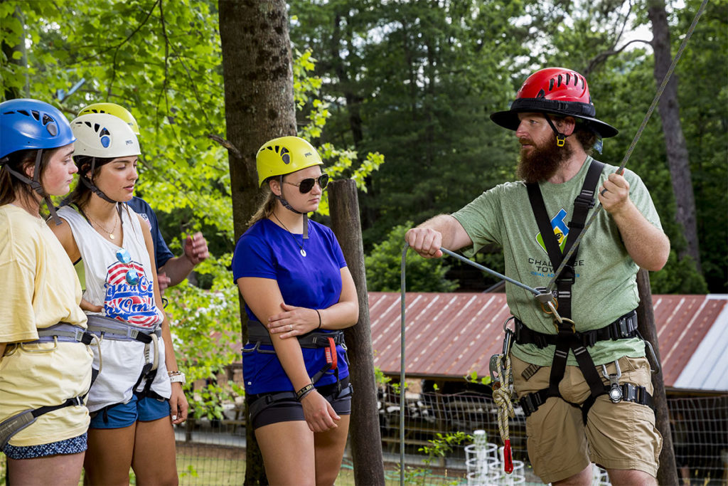 Trainer instructing camp staff on proper belay techniques - in Summer