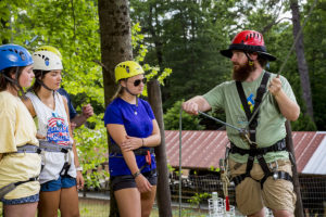 Trainer instructing camp staff on proper belay techniques - in Summer
